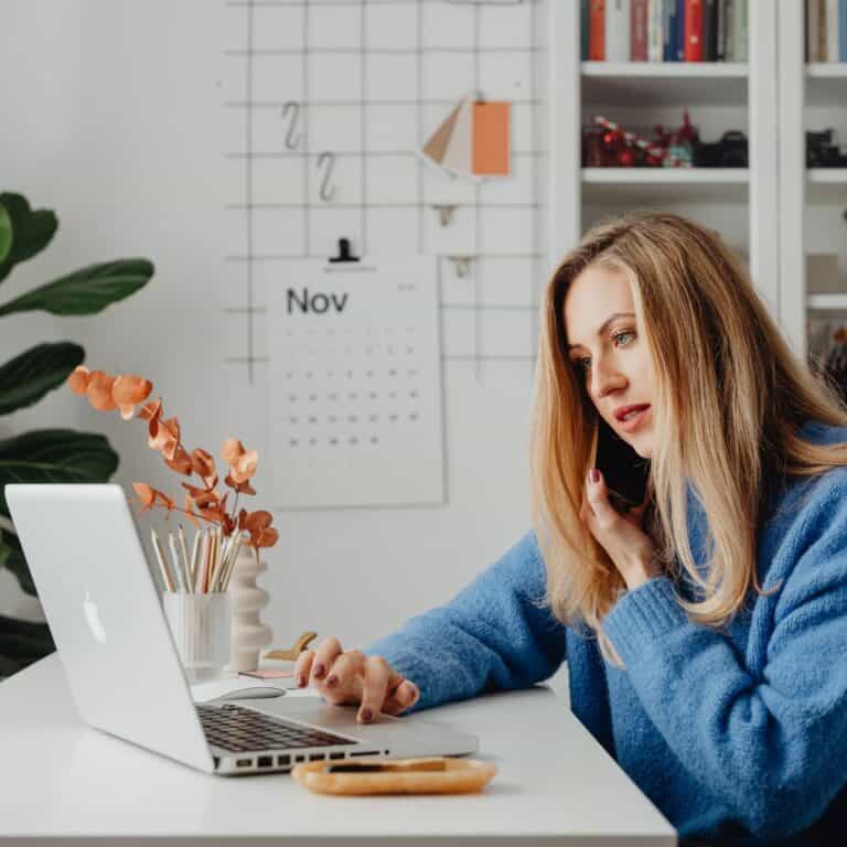 Woman working on laptop with website launch checklist in background, small business SEO.
